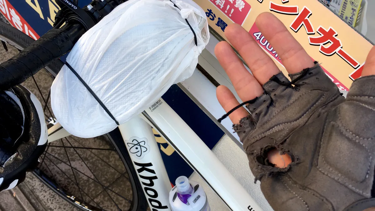 落車で破れたグローブとハンドルに固定された無印のスリッパ